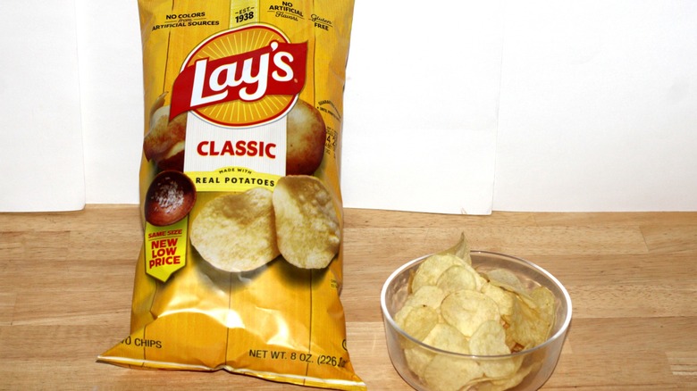 A bag of Lay's Classic potato chips beside a bowl full of chips