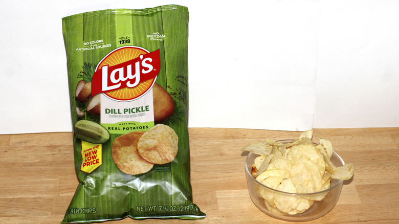 A bag of Lay's Dill Pickle potato chips beside a bowl full of chips