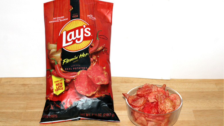 A bag of Lay's Flamin' Hot potato chips beside a bowl full of chips