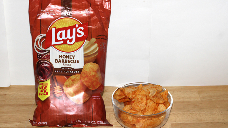 A bag of Lay's Honey Barbecue potato chips beside a bowl full of chips