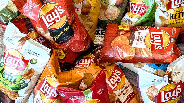 A messy pile made up of bags of Lay's potato chips of various flavors