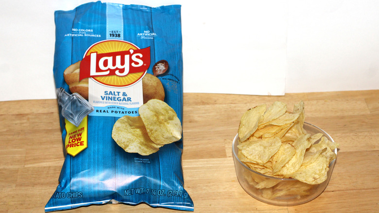 A bag of Lay's Salt & Vinegar potato chips beside a bowl full of chips