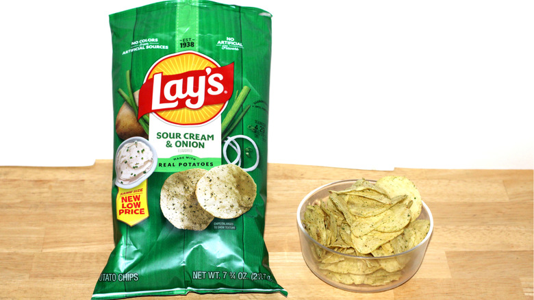 A bag of Lay's Sour Cream & Onion potato chips beside a bowl full of chips