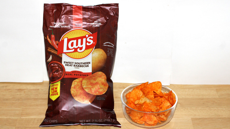 A bag of Lay's Southern Sweet Heat Barbecue potato chips beside a bowl full of chips