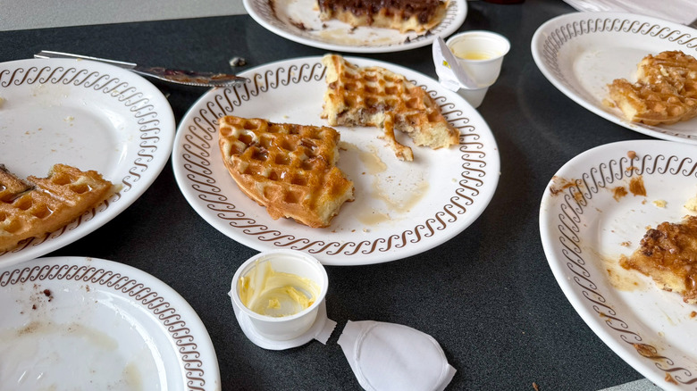 Several half eaten waffles on a Waffle House table on white plates