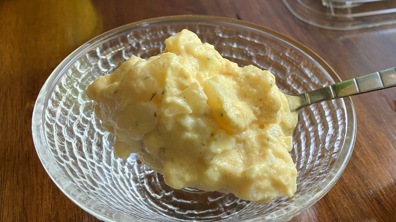 A spoonful of Walmart's Freshness Guaranteed Potato Salad hovers over a glass bowl