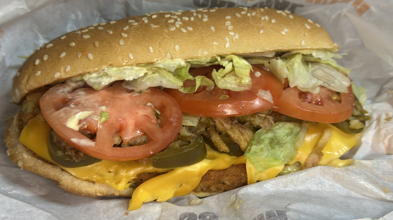 Burger King Loaded Jalapeño original chicken sandwich with ingredients exposed, like sliced tomatoes, lettuce, jalapeños, and cheese