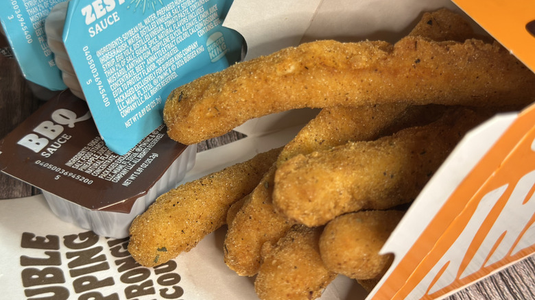 Burger King Chicken Fries takeout container on its side with chicken fries spilling out