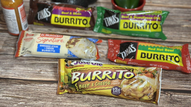 Frozen beef burritos lined up on a wooden table