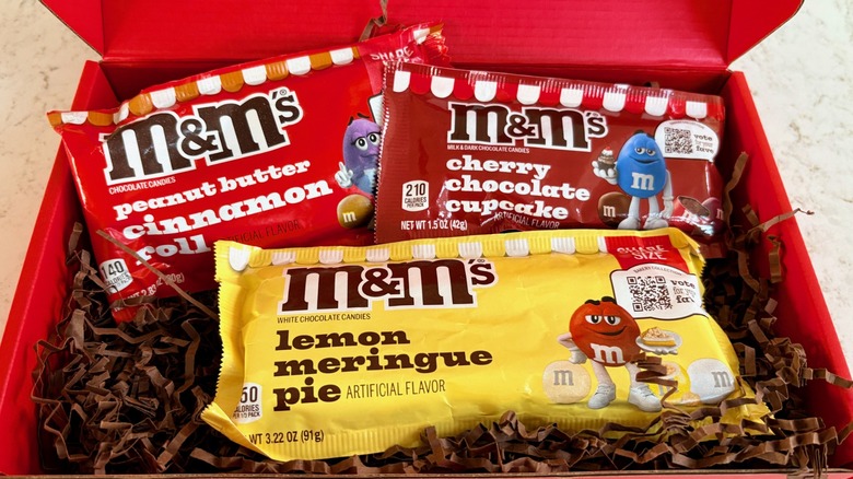 A red box filled with M&M's Bakery Collection peanut butter cinnamon roll, cherry chocolate cupcake, and lemon meringue pie