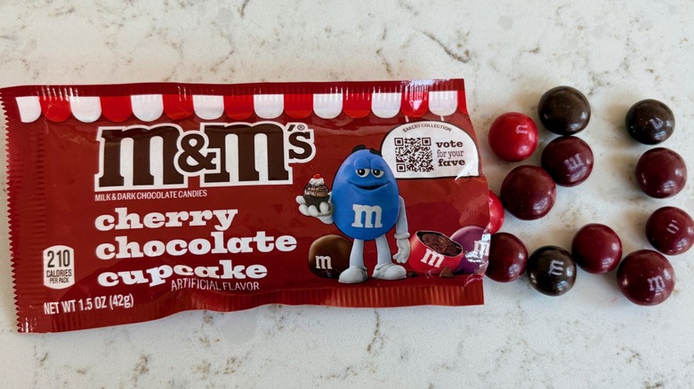 An open bag of M&M's cherry chocolate cupcake candies poured on a counter