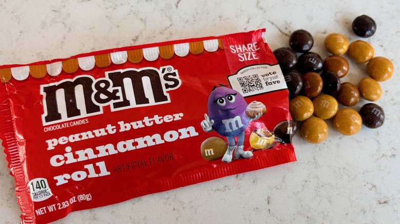An open bag of M&M's peanut butter cinnamon roll candies poured on a counter