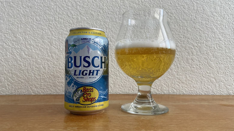 Busch Light can beside tulip glass half-full of beer