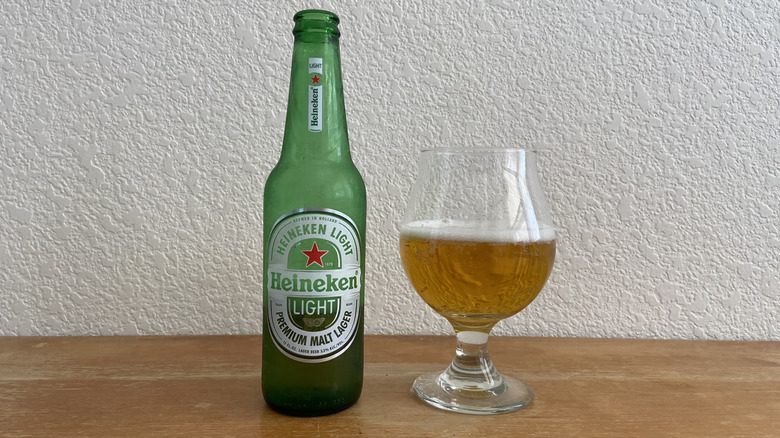 Heineken Light bottle beside tulip glass half-full of beer
