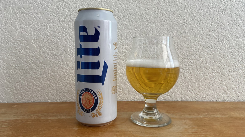 Miller Lite can beside tulip glass half-full of beer