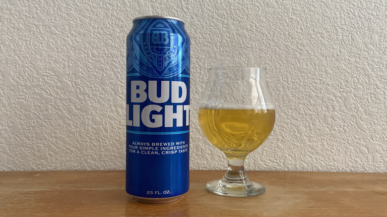 Bud Light tall can beside tulip glass half-full of beer