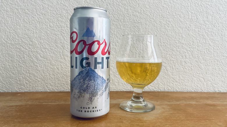 Coors Light tall can beside tulip glass half-full of beer