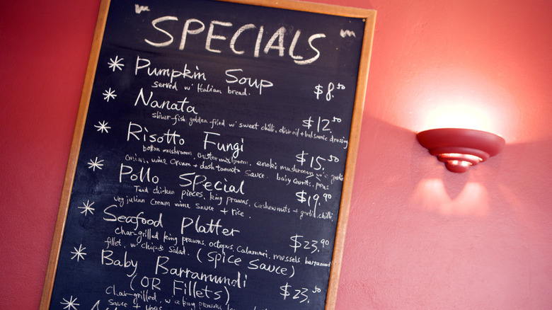 A specials board on the red wall of a restauranta