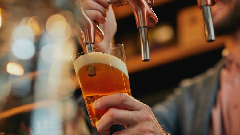 Person pouring beer with tap in the glass