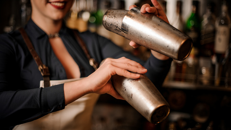 Bartender mixing two cocktails together in a shaker