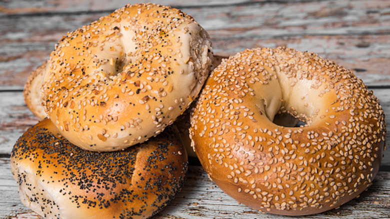 Several New York-style bagels stacked on top of each other on a farmhouse style table.