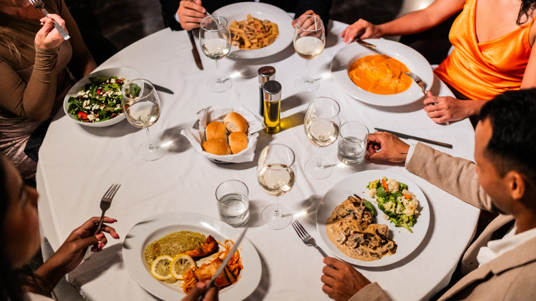 Overhead shot of people eating various dishes at a restaurant table