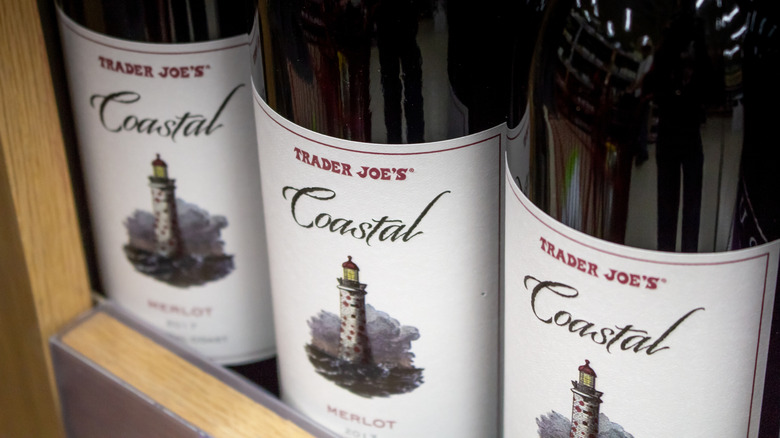 Three bottles of Trader Joe's Coastal Merlot wine on a store shelf.