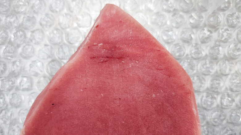 A low quality tuna steak with visible veins, on bubble wrap