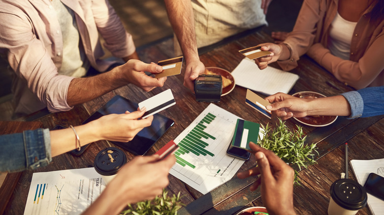 Restaurant patrons hand several credit cards to a server