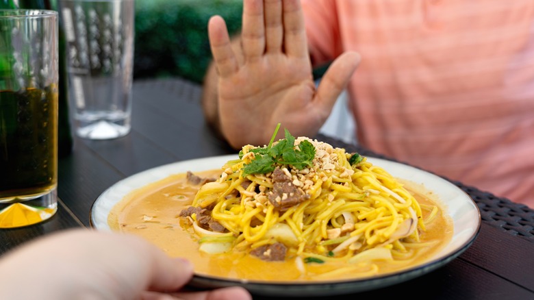 Person rejecting plate of food in restaurant
