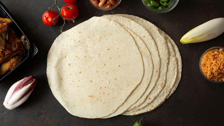 Several flour tortillas layered on each other surrounded by various toppings