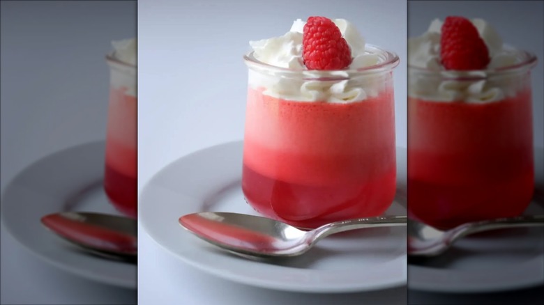 Three layer Jell-O with whipped cream on top and a raspberry garnish