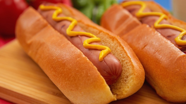 Hot dogs in buns drizzled with mustard