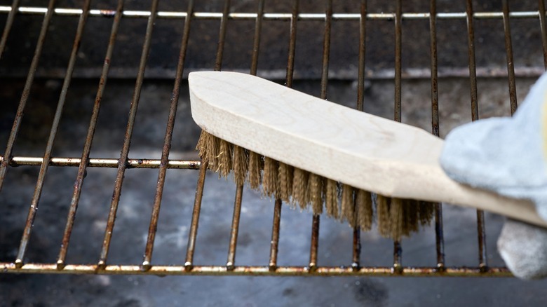 Person cleaning grill with brush