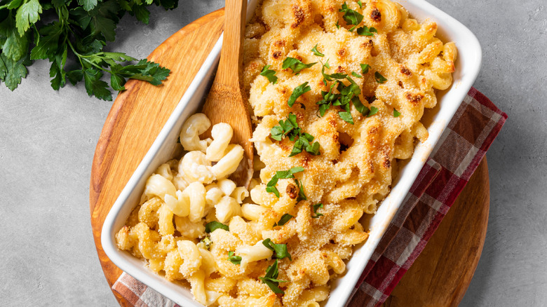 Baked macaroni and cheese in a white pan with fresh herbs