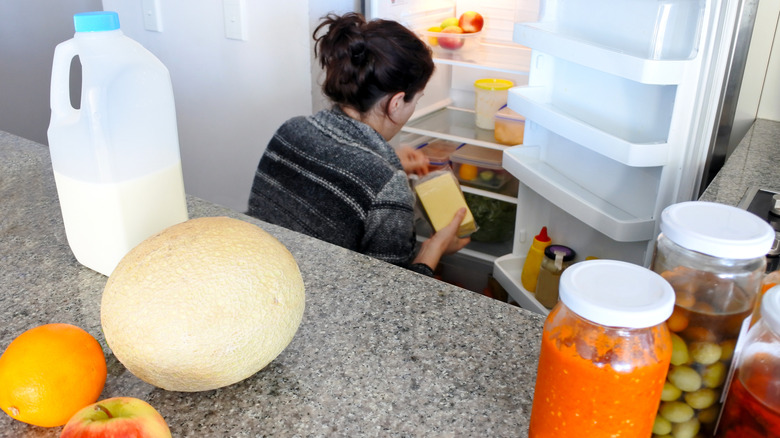 Person cleaning out a fridge with food items on a counter