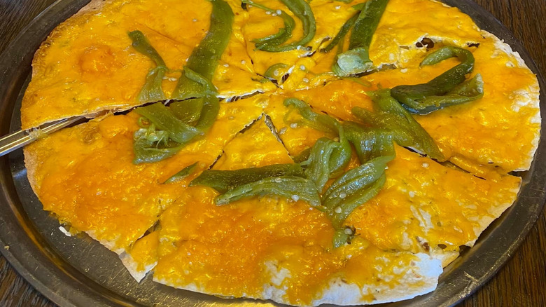 An Arizona cheese crisp, cut and topped with green peppers