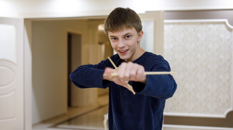 Teenage boy playing with chopsticks