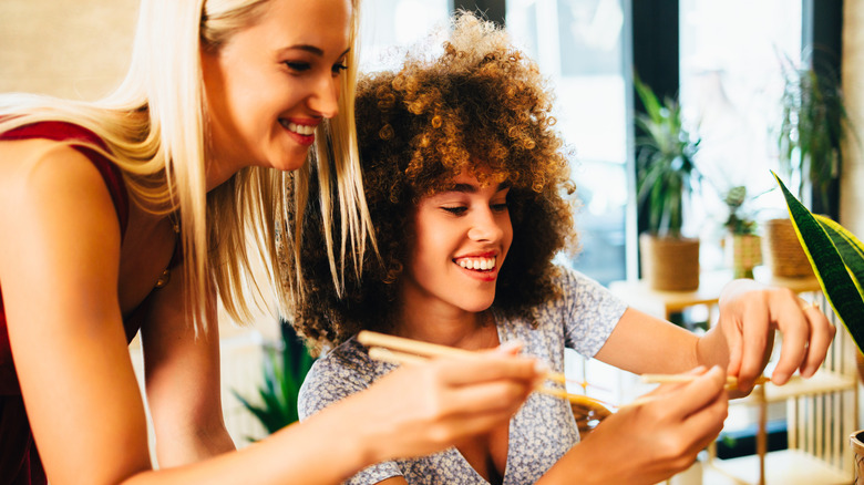 Two women looking at their chopsticks