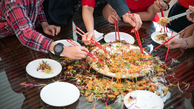 People making a mess of a shared meal with chopsticks