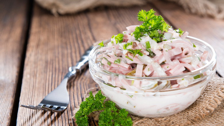 A small bowl of fleischsalat on at table, garnished with parsley