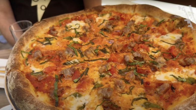 Close-up of a thick crust pizza with cheese, basil, and meat