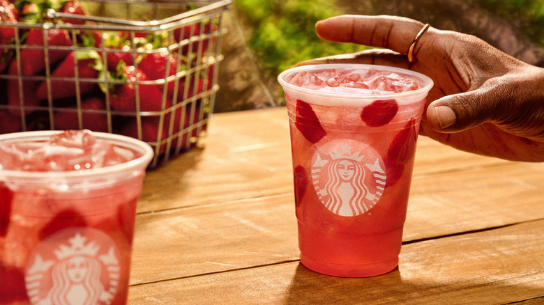 Hand reaching for a Strawberry Açaí Lemonade Starbucks Refreshers