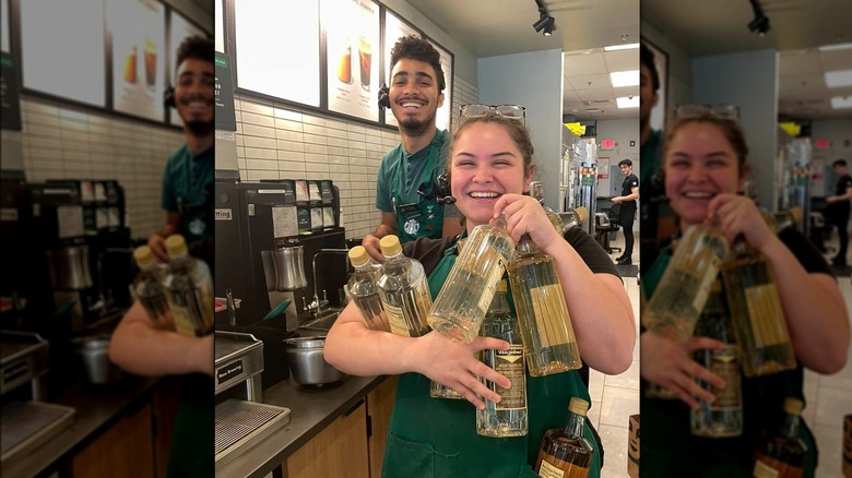 Starbucks barista holding many bottles of syrups