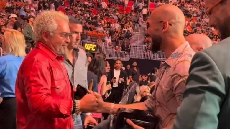 Guy Fieri shaking hands with Andrew Tate at a UFC match