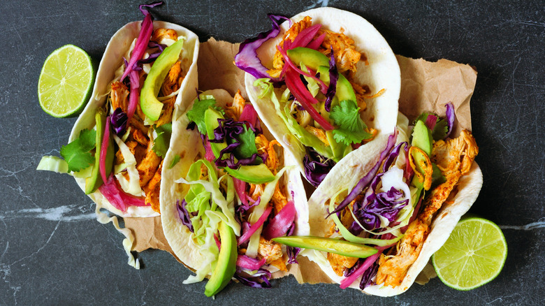 Chicken tacos with avocado, red cabbage, and lime