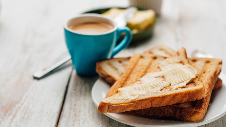 Breakfast with coffee and buttered toast on gray wooden table
