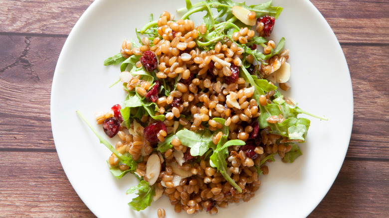 Farro salad with arugula and almonds on white plate