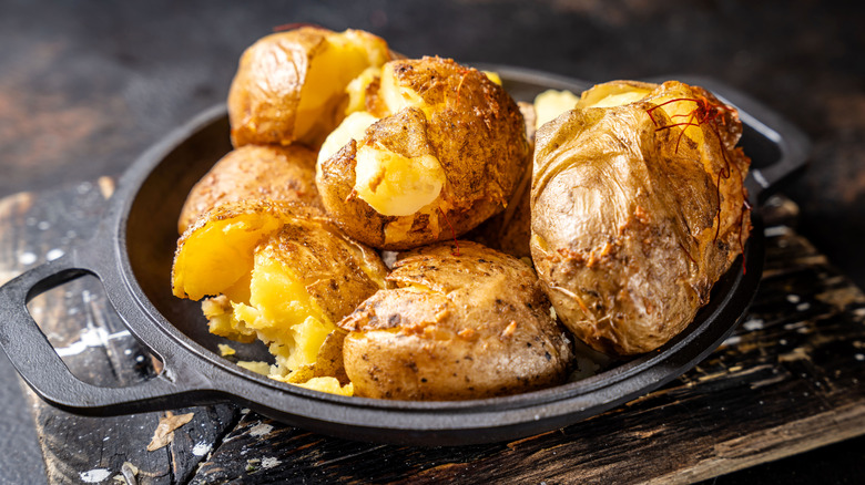 Golden baked potatoes with crispy skin served in a rustic cast iron pan