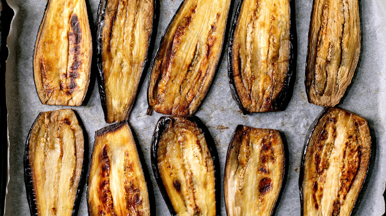 Roasted slices of eggplant on a parchment covered baking sheet